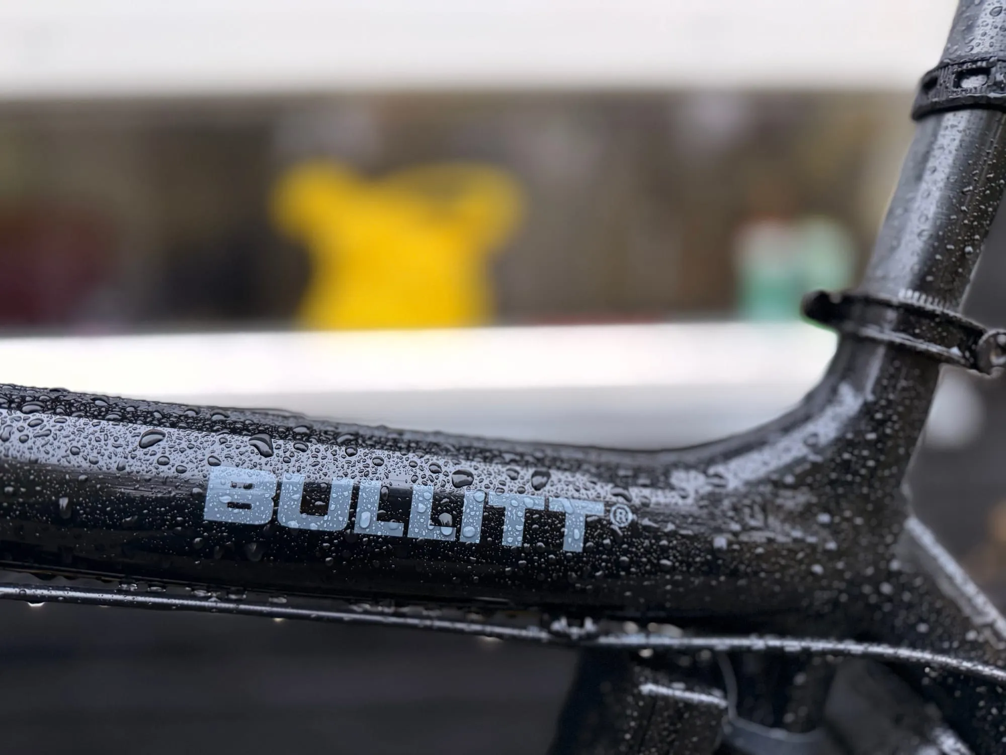 Close-up of the wet black Bullitt frame, the BULLITT logo covered in rain drops.